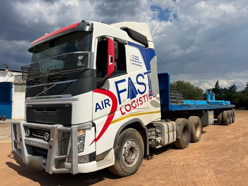 Volvo FH coupled to a blue flat-deck trailer